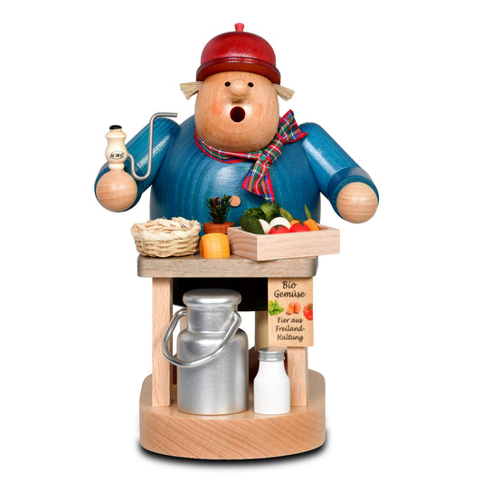 KWO Räuchermann Bio-Bauer aus der Serie Die Dicken (Art. 21445) steht an einem Marktstand aus Holz mit einer silbernen Milchkanne, Gemüse und einem Eierkorb. Original erzgebirgische Volkskunst aus Olbernhau.
